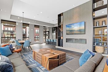 A modern living room with a grey sofa, a wooden coffee table, and a large painting on the wall.